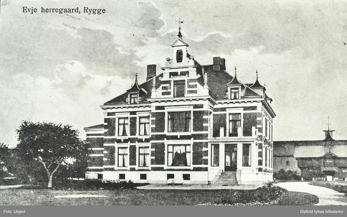 Postkort av Evje herregård i Rygge. Stabbur og uthus i bakgrunnen.