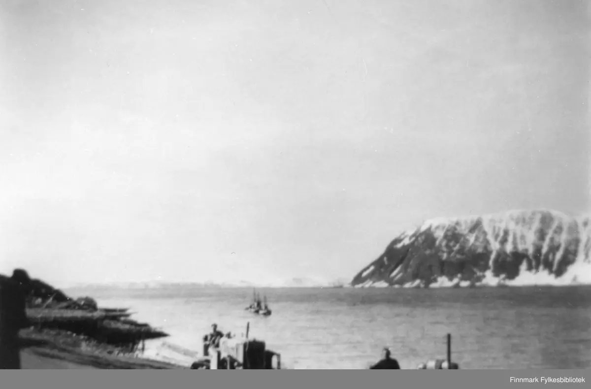 Landskapsbilde med Digermulen ytterst i Langfjorden i Gamvik kommune.  I forgrunnen sees noen med anleggsmaskiner i sjøkanten, et par fiskeskøyter er på vei ut fjorden. Bildet er muligens tatt i begynnelsen av 50-årene. En informant forteller at et hus bygd etter frigjøringen, ble revet utenfor Langfjordnes og så transportert til Sandholmen i Hopsfjorden. Det er også en mulighet for at bildet er tatt under oppførelsen av huset, når bygningsmaterialene skulle i land fra båtene som er på vei ut fjorden etter å ha brakt lasten i land. 

Det står litt om Langfjordnes i denne bloggen: http://www.langfjordnes.com/39827755