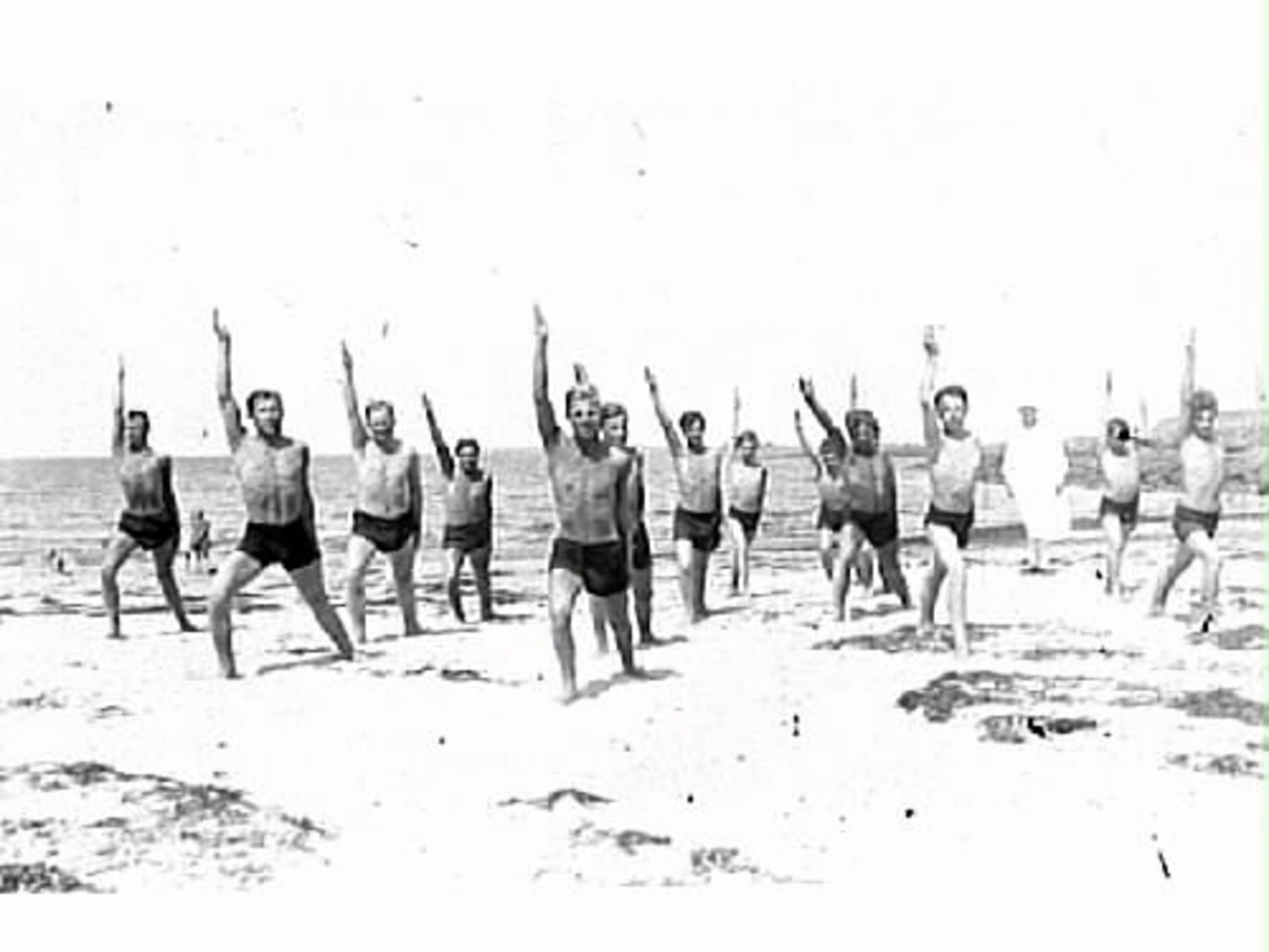 Män, patienter från Kustsanatoriet Apelviken, gymnastiserar på stranden i Lilla Apelviken. Vården inriktades från 1910-talets mitt även mot sjuka i ben- och ledtuberkulos då även äldre patienter började tas emot.