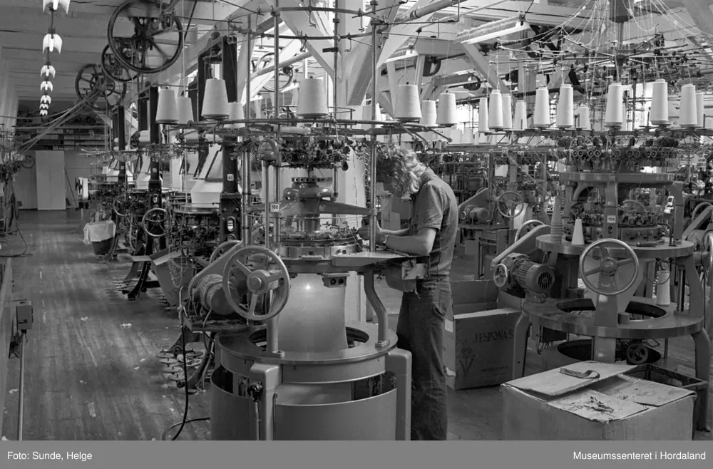 Arbeidsliv ved Salhus Tricotagefabrik i Salhus, Bergen i 1976. Arbeidar ved strikkemaskin på strikkeloftet ved Salhus Tricotagefabrik.