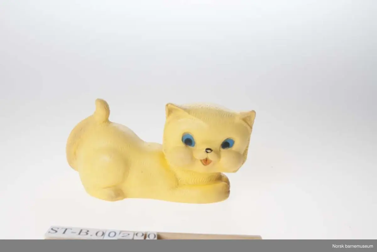 Vinylfigur av en katt. Pip mangler (virker). Gul, blå, rød (famlet tungem svart nese.