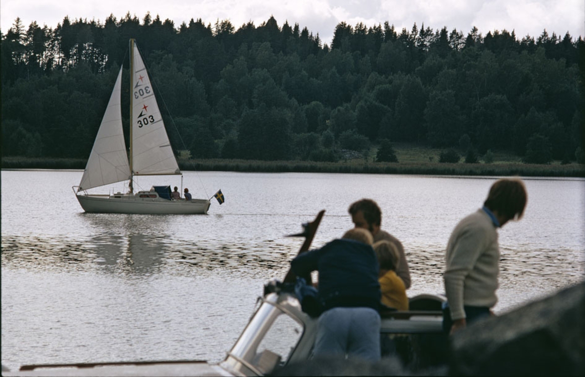 En Albin Viggen seglar i Vänern. I förgrunden personer ombord på en Albin 25. Marknadsföringbild.