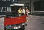 Två män och en kvinna vid en personbil, Lancia Fulvia, utanför Albin Marins lokaler i Kristinehamn.