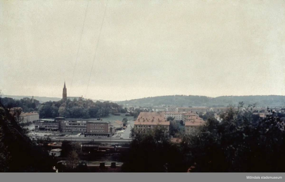 Vy från Enerbacken, åt nordväst över centrala Mölndal, 1970-tal. Till vänster ses Fässbergs kyrka och Mölndals stadshus. Rakt fram ligger lägenheter utmed Knarrhögsgatan.