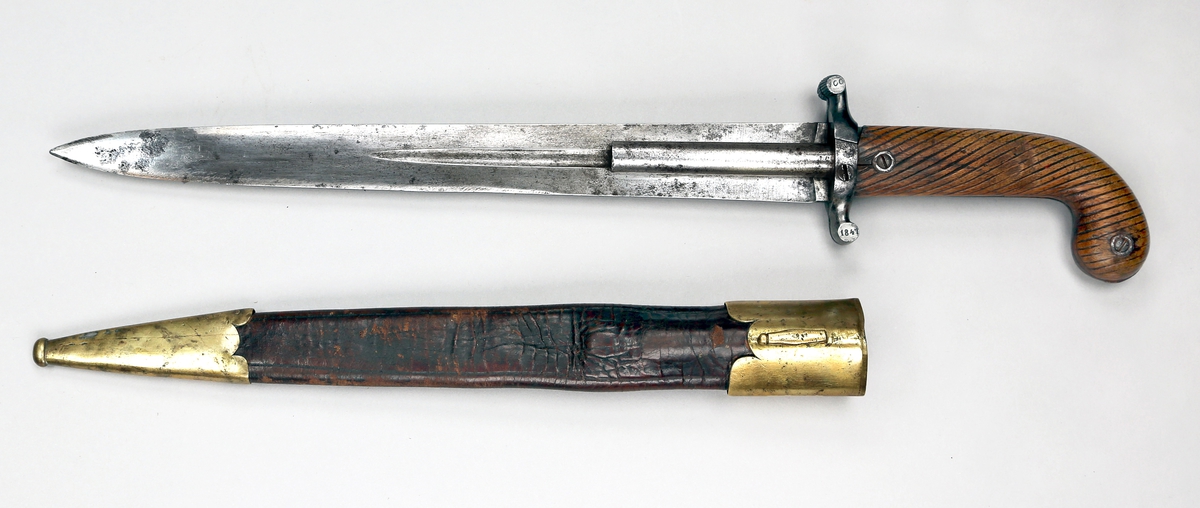 Kombinert stikkevåpen og skytevåpen, med tveegget klinge og ett løp på hver side. Pistolen er av 10 mm kaliber. Håndtaket er av tre. Balgen er av lær med messing