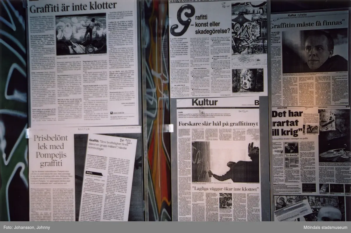 Tidningsurklipp. Från utställningen "Alltså finns jag" som handlade om graffitikultur. Pågick 25 januari - 25 maj 2003 på Mölndals Museum (senare Mölndals stadsmuseum). Produktionen var ett samarbete mellan Mölndals Museum, Vitlycke museum, Bohusläns museum, Västergötlands museum och Konstkonsulenterna i Västra Götalandsregionen.