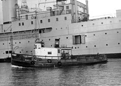 Bogserbåten FANNY passerar framför ubåtsdepåfartyget PATRICI