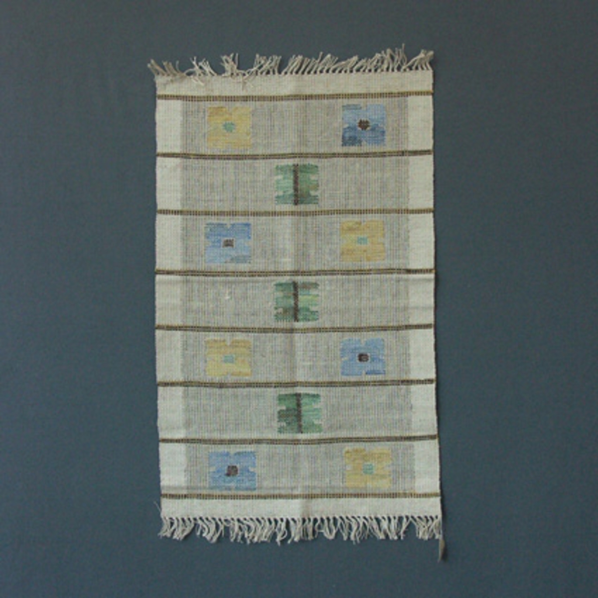 Löpare i HV-teknik med lingarn i varpen och ull- och lingarn i inslaget och mönster i grönt, blått, gult och brunt.Pris 14:- N x dd.Etikett från Statens livsmedelskommission är fastsydd, kupongfritt, svenskt handgjort.