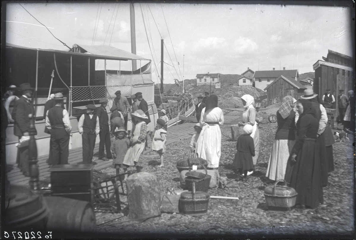 Bohuslänskt fiskeläge ungefär 1920. Passagerarna, finklädda för resan, gör sig klara att gå ombord.