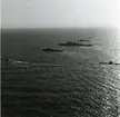 Flygfoto visande:
En kryssare av Tre Kronor-klass, en äldre stadsjagare, en nyare stadsjagare av Visby-klass samt tre ubåtar.