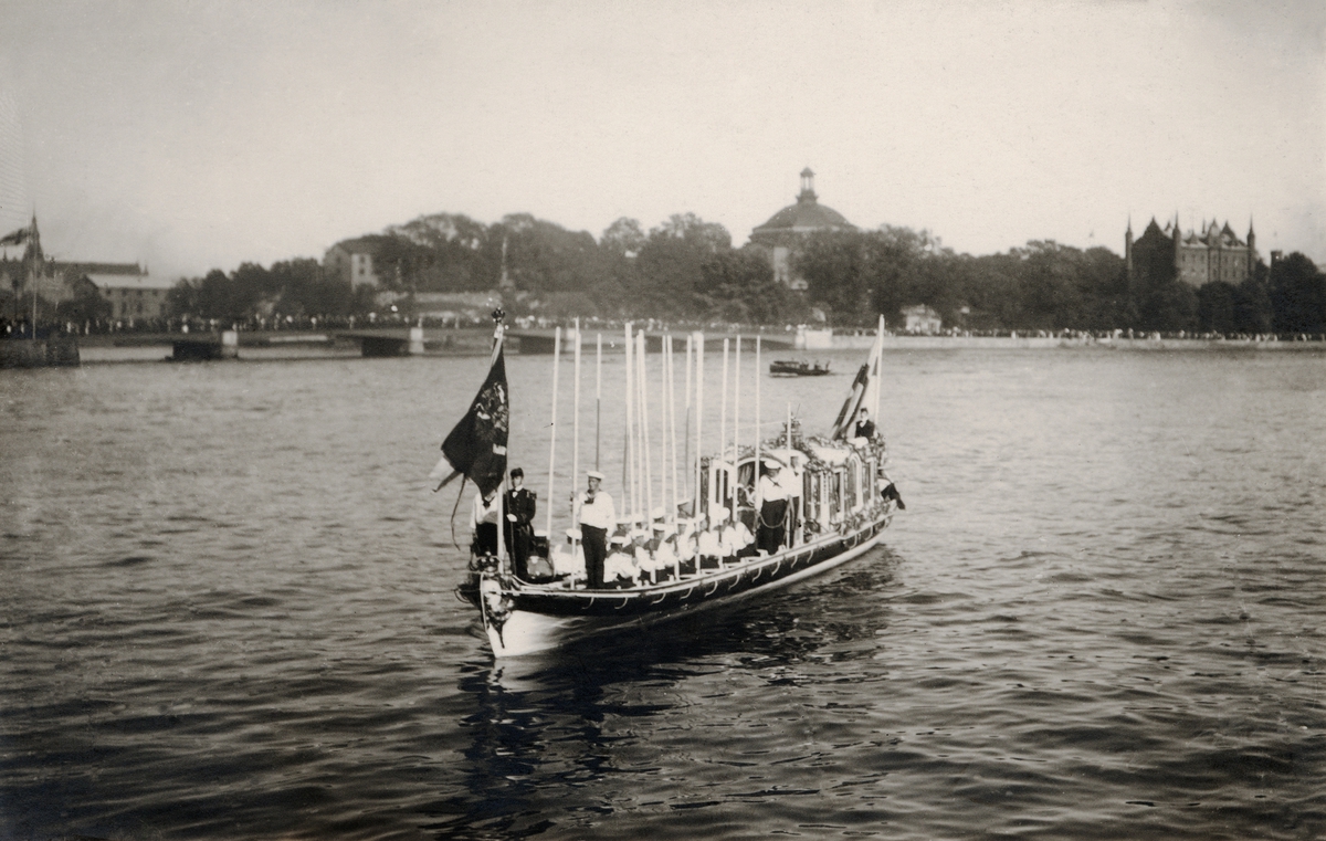 Kungliga roddslupen VASAORDEN på väg till Logårdstrappan med det ryska kejsar- och det svenska kungaparet ombord den 26 juni 1909. Denna ursprungliga slup förstördes i branden på Galärvarvet 1921 och ersattes till följande år av den replik som i dag ännu existerar i Båthallen.