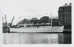 Foto i svartvitt visande passagerarmotorfartyget CHRISTOFER POLHEM vid Nybrokajen, Stockholm, 1955.