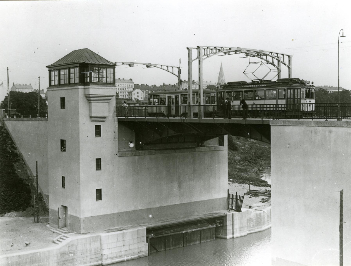 Hammarbyleden och Skanstullsbron omkring 1930. Spårvagnen trafikerade då sträckan Slussen--Enskede via Katarinavägen--Renstiernas gata--Ringvägen.
Motorvagnen från år 1924. Släpvagnen från år 1923 kallad för "Två rum och kökvagn".