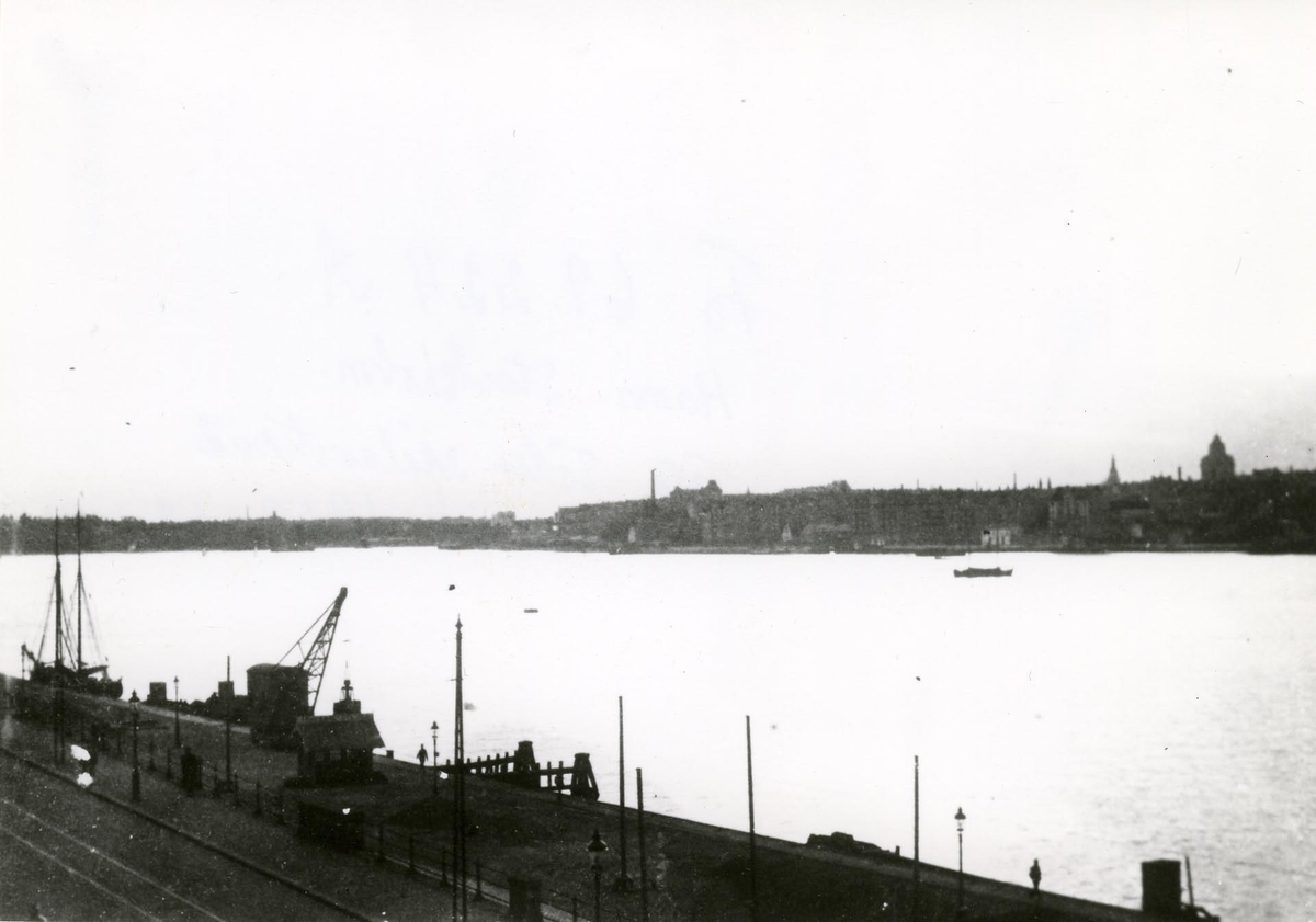 Fotot taget i skymningen från Sandins föräldrahem Söder Mälarstrand 10 - 12, med utsikt över Riddarfjärden. I förgrunden S. Mälarstrands kaj. Omkring 1918-20.