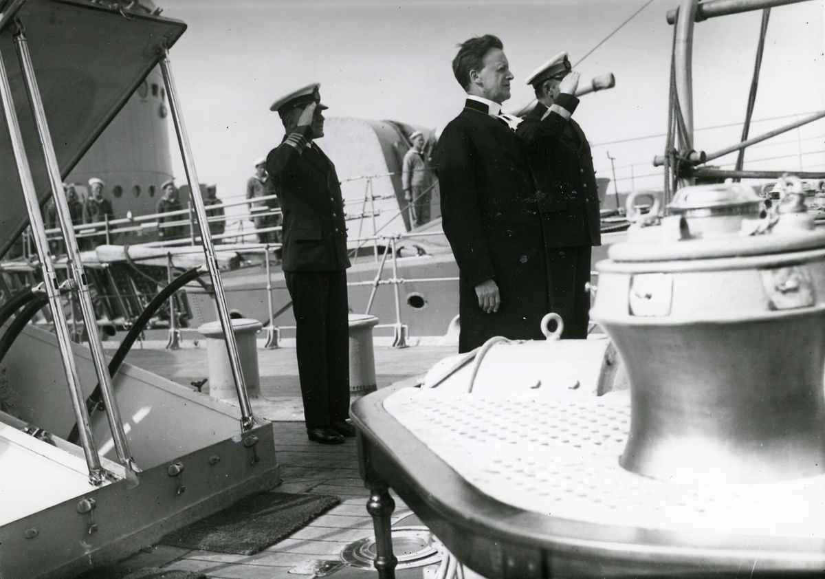 Präst tillsammans med kommendör och konteramiral på däck.