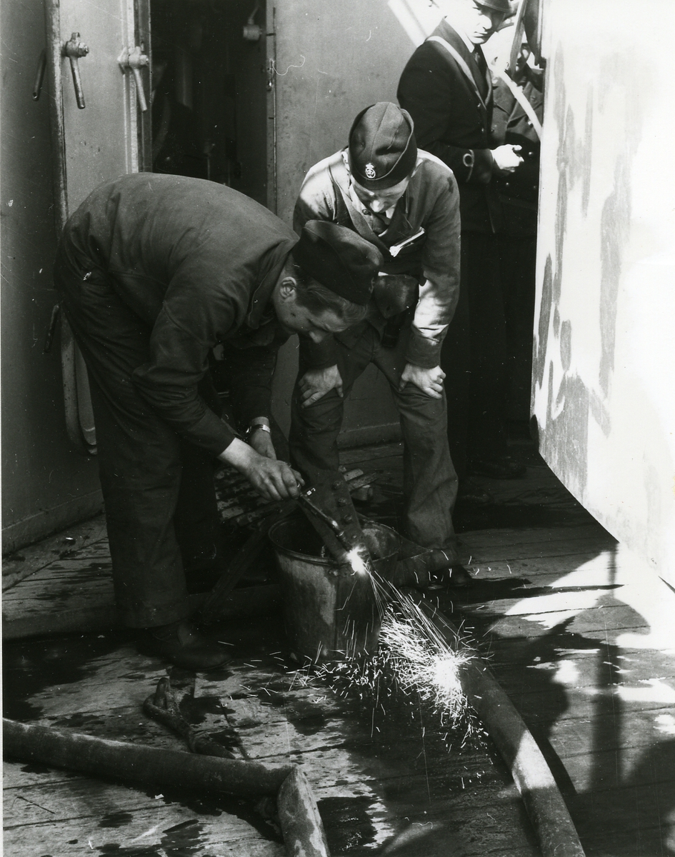 Besättningsman utför svetsningsarbete på däck.