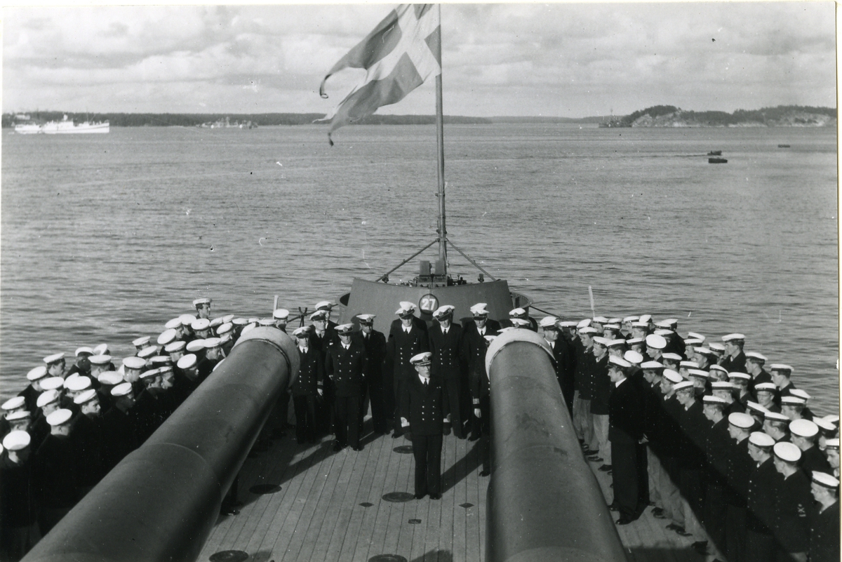 Konteramiral talar till besättningen på akterdäcket till ett pansarskepp.