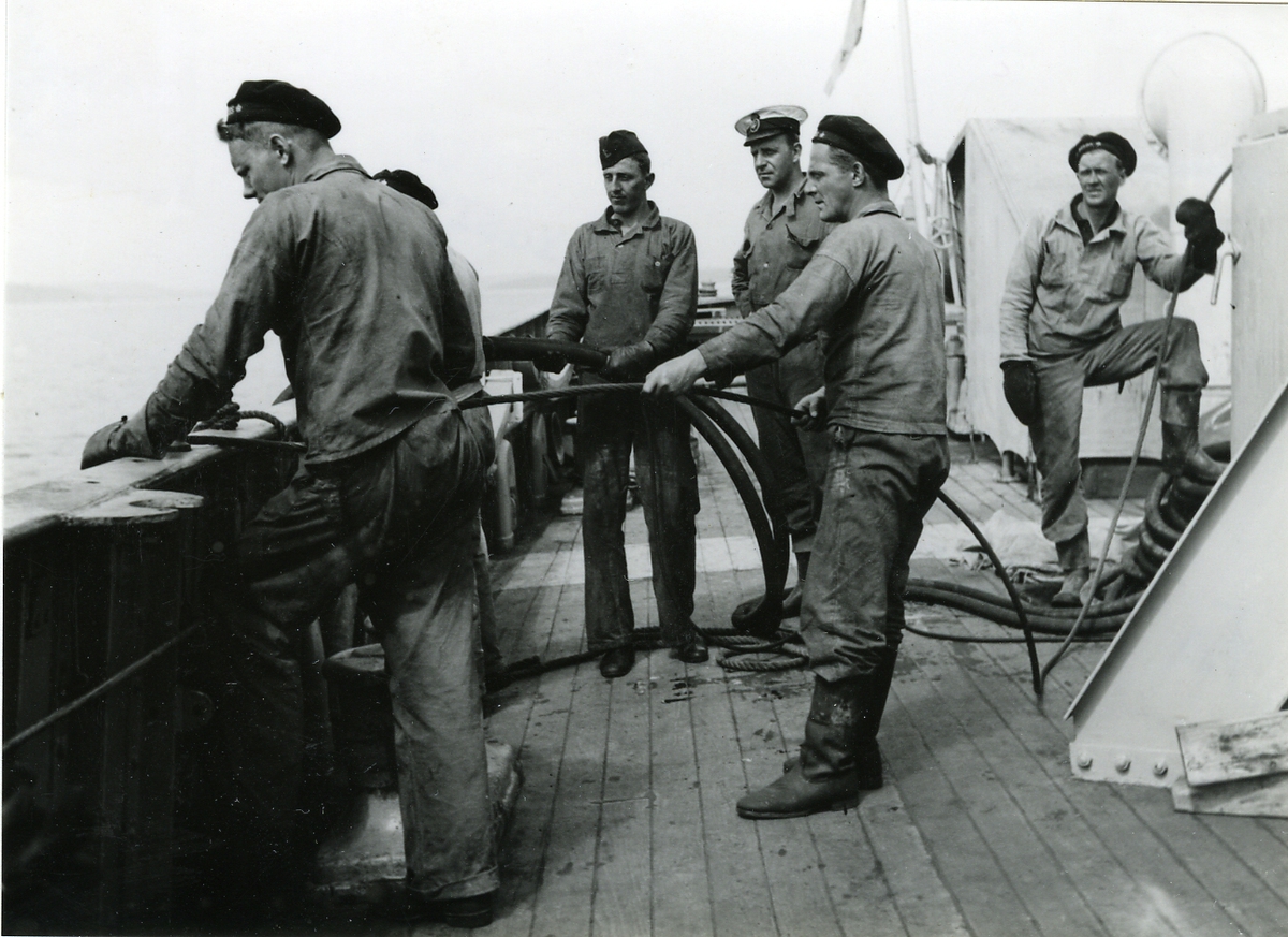 Ombord på bärgningsfartyget Belos. Manskap på däck sköter slangar och linor till dykarklocka.