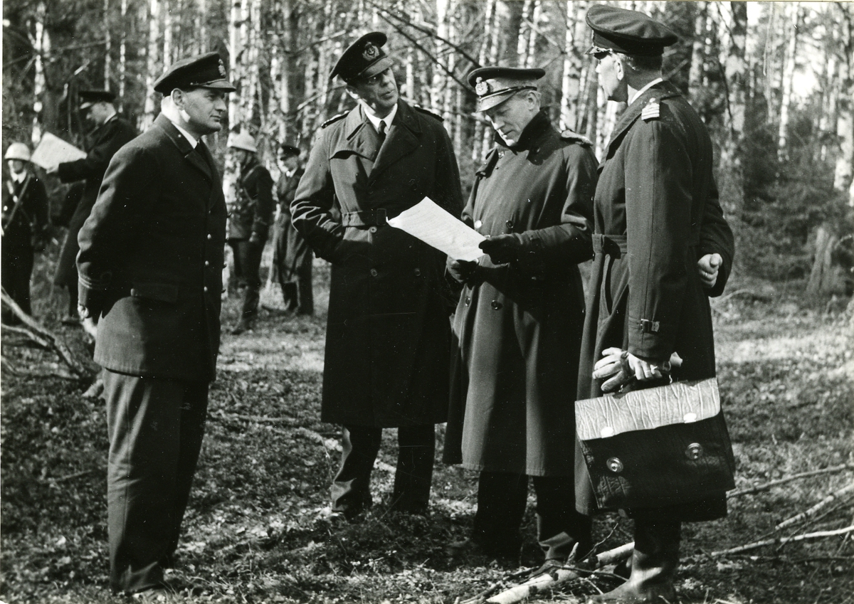 Konteramiral Yngve Ekstrand läsande ett papper omgiven av andra officerare.