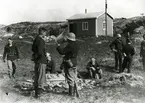 Manskap som vilar och dricker vatten vid en brunn, under manöver på skärgårdsö.