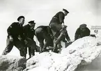 Manskap monterar artilleripjäs på land.
