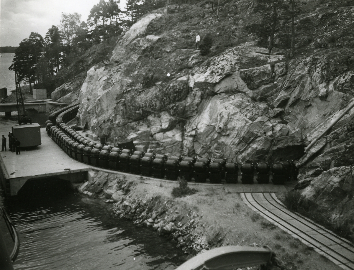 Kryssaren Göta Lejon tar ombord minor 1948. Minorna körs ut på kajen från ett bergrum.