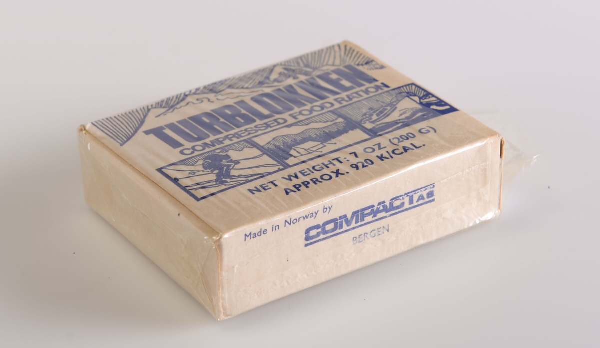 Rektangulær emballasje av papp med innhold av åtte biter konsentrert mat. Esken er hvit med blå skrift. Pakningen har vært tett innpakket i plast, denne er gått noe i oppløsning.