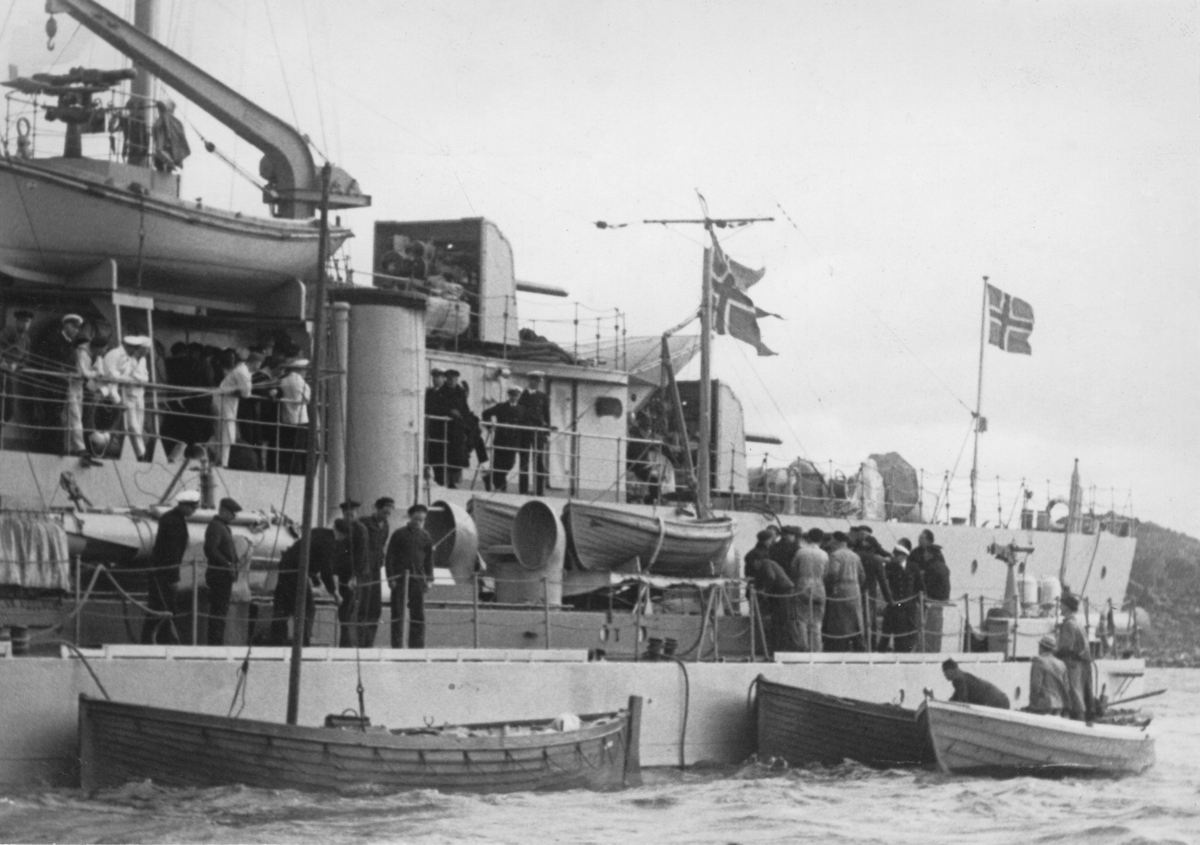 "Besättningen från S/S Nyland som torpederades den 28 september 1939, har omhändertagits av en norsk jagare, som kom till undsättning."

Det större norska fartyget är troligen i själva verket minfartyget OLAV TRYGGVASSON. Närmare kameran en torpedbåt.