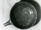 Djurhamn, fynd 97/1964.
Stekfat med handtag och tre små fötter av rött lergods, glaserat brunt inuti och längs yttersidan, inte på undersidan.
Mynningsdiameter c:a 31 cm, höjd 10 cm, handtagets längd c:a 10 cm.
Kärlkanten något utvikt till pip.
Bilden tagen uppifrån.