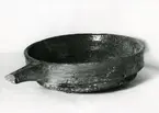 Djurhamn, fynd 97/1964.
Stekfat med handtag och tre små fötter av rött lergods, glaserat brunt inuti och längs yttersidan, inte på undersidan.
Mynningsdiameter c:a 31 cm, höjd 10 cm, handtagets längd c:a 10 cm.
Kärlkanten något utvikt till pip.
Bilden tagen från sidan, något uppifrån.