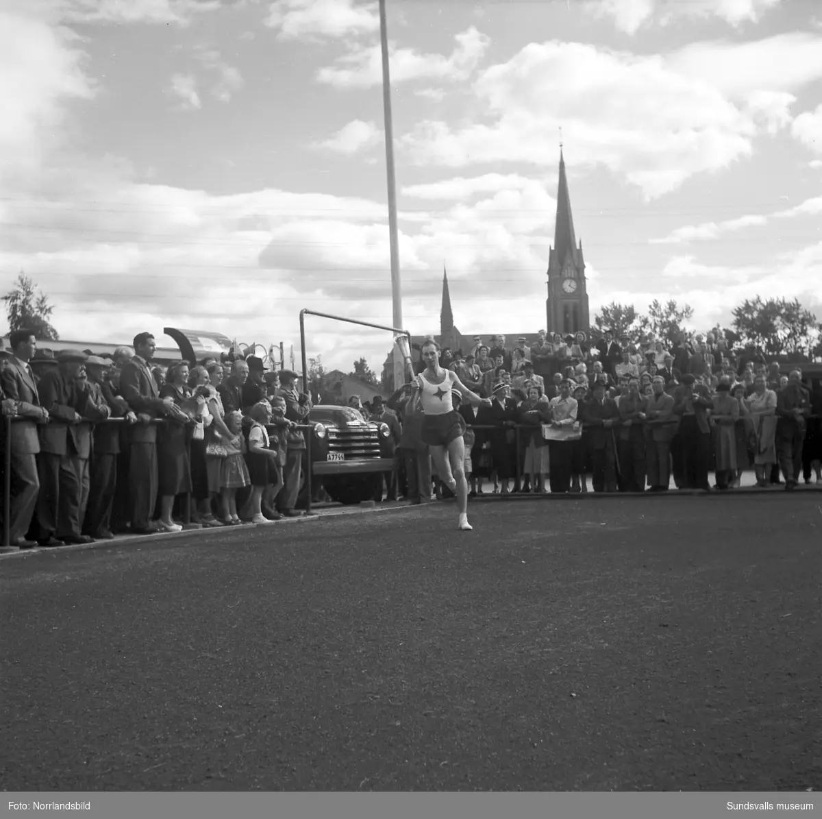 Den olympiska elden passerar Sundsvall inför sommarspelen i Helsingfors 1952 med högtidlig stafettväxling i Idrottsparken. In på arenan förs facklan av IFK-löparen Eric Nilsson, som är uttagen till Olympiaden på 3000 meter hinder. Därefter tar SAIK-brottaren och OS-silvermedaljören från 1936, John Nyman över för att påbörja facklans färd vidare mot Härnösand och Kramfors.