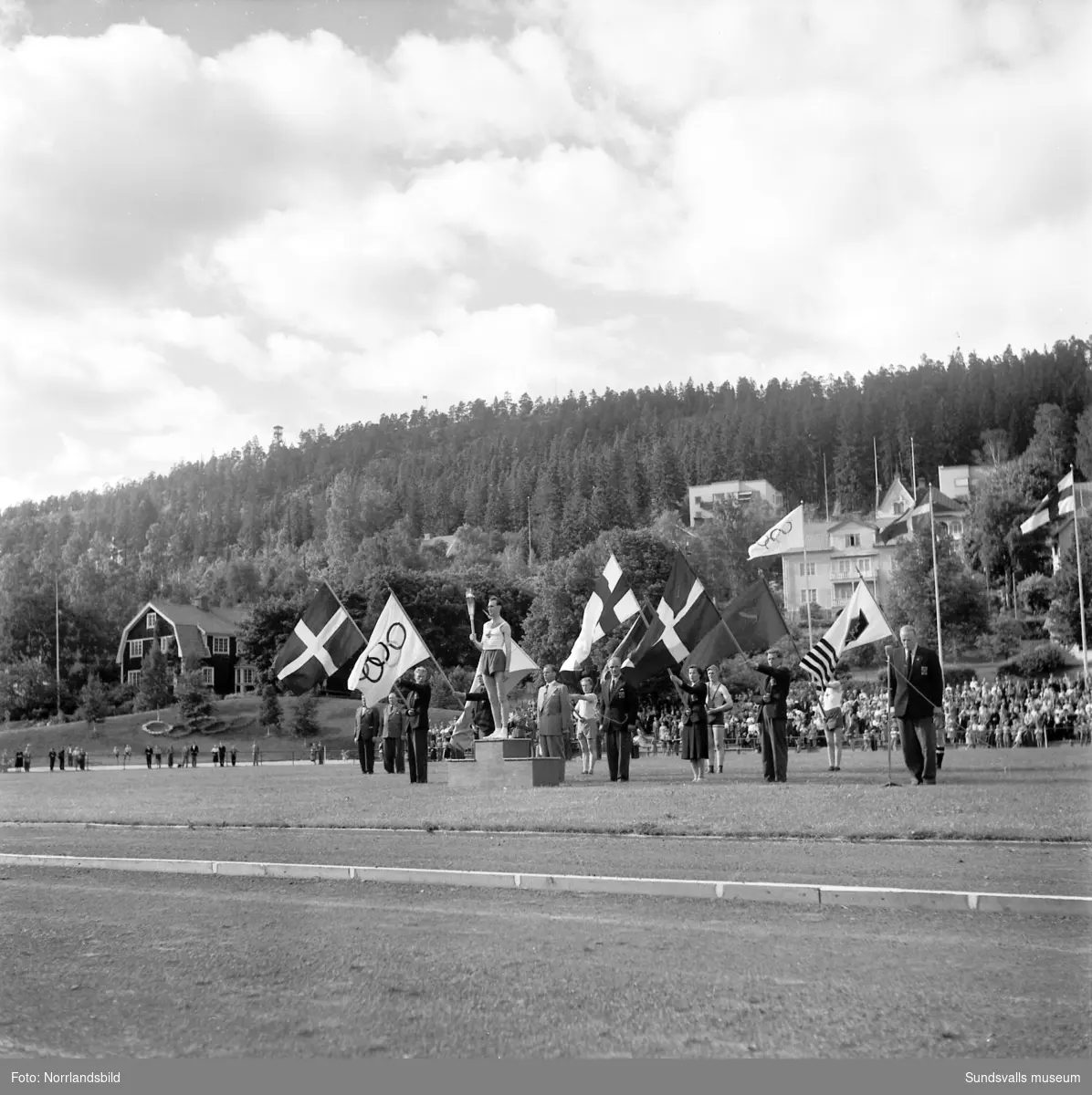 Den olympiska elden passerar Sundsvall inför sommarspelen i Helsingfors 1952 med högtidlig stafettväxling i Idrottsparken. In på arenan förs facklan av IFK-löparen Eric Nilsson, som är uttagen till Olympiaden på 3000 meter hinder. Därefter tar SAIK-brottaren och OS-silvermedaljören från 1936, John Nyman över för att påbörja facklans färd vidare mot Härnösand och Kramfors.