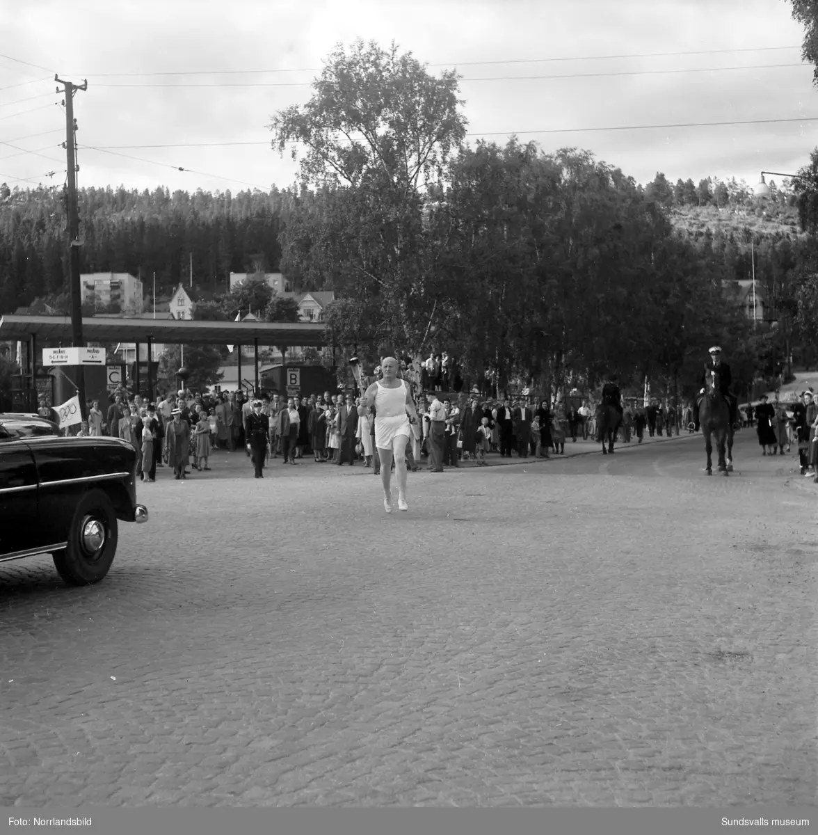 Den olympiska elden passerar Sundsvall inför sommarspelen i Helsingfors 1952 med högtidlig stafettväxling i Idrottsparken. In på arenan förs facklan av IFK-löparen Eric Nilsson, som är uttagen till Olympiaden på 3000 meter hinder. Därefter tar SAIK-brottaren och OS-silvermedaljören från 1936, John Nyman över för att påbörja facklans färd vidare mot Härnösand och Kramfors.