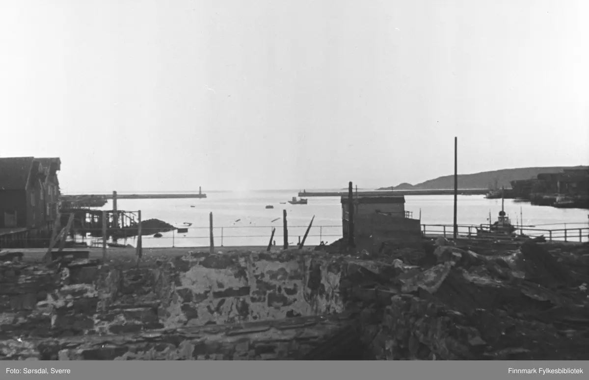 Vardø i ruiner etter krigen. Ser havna og moloen. En skjå står igjen ...