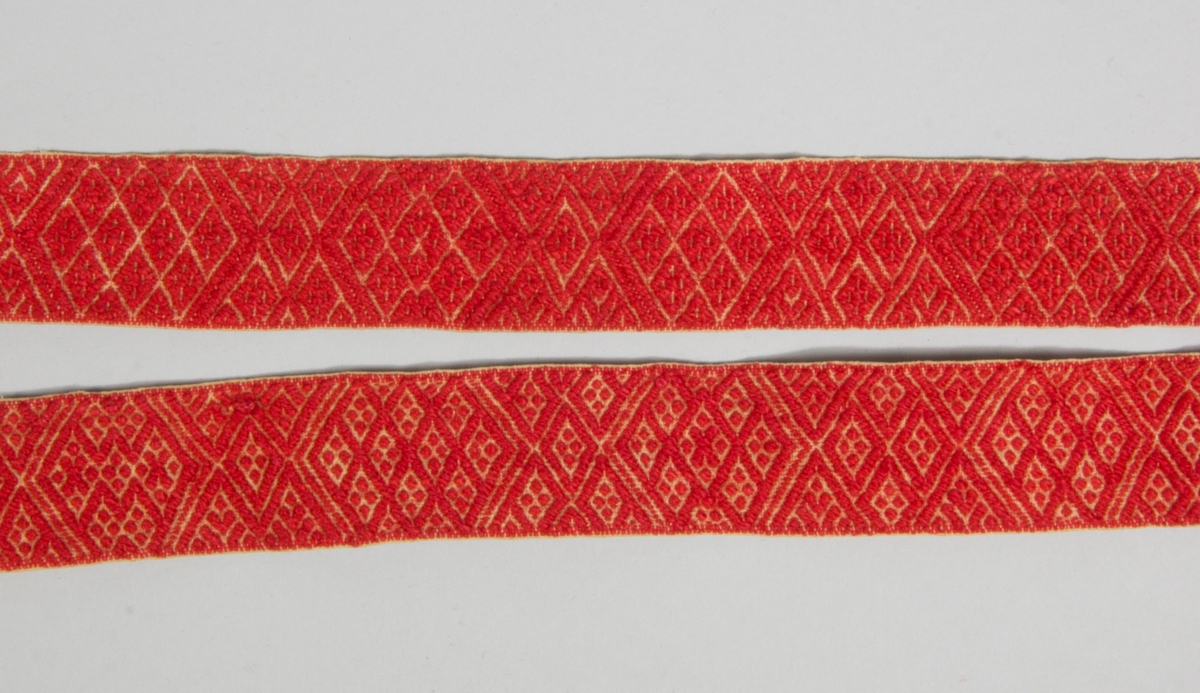 Kjolsäck till dräkt för kvinna från Rättviks socken, Dalarna. Modell med avskuret framstycke. Tillverkad av vitt fårskinn, med applikationer av ylletyg, kläde, i rött, grönt och gult, fastsydda med lingarn, efterstygn. Centralt placerad stor hjärtblomma med omgivande mindre blommor i hörnen och andra figurer. Broderi utfört med silkegarn i många färger: flätsöm, plattsöm, sticksöm. Märkt med klippta tecken: BJ 1868. Extra dekoration av sju vita porslinsknappar. Ovanför applikaionen en remsa rött kläde med flätsöm, ovanför den en "grind" flätad av smala remsor rött och grönt kläde samt vitt skinn. Framstycket fodrat med vitt fabriksvävt bomullstyg, tuskaft. En remsa rött kläde inlagd i sido- och bottensöm. I nederkanten fäst tre tofsar av olika tyger. Överstycke av bomullstyg, tryckt mönster i flera färger på röd botten, kattun. Bakstycke av vitt, rakat fårskinn. Axelband handvävt, med plockat mönster av rött ullgarn på vit botten. Vid bandets fäste sitter tre bollar av ullgarn.
