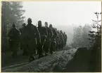 Värnpliktiga marscherar vid morgongryning.