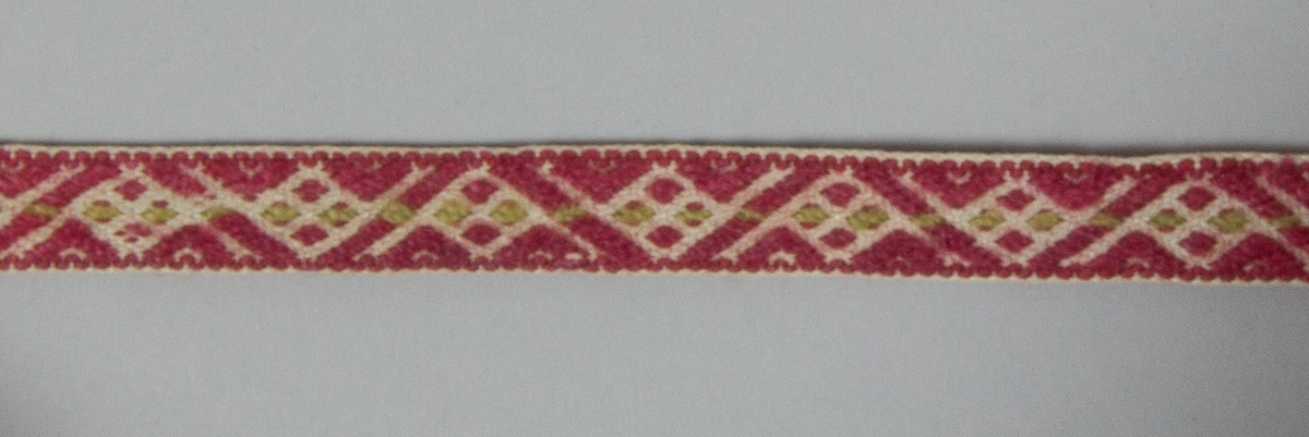 Kjolsäck till dräkt för kvinna från Mora socken, Dalarna. Modell med avskuret framstycke. Tillverkad av handvävt linnetyg, vävt i korndräll. Breda fållar i överkanterna. Handsydd förstärkning ovanför sidsömmarna. Axelband handvävt med plockat mönster av rött och lite grönt ullgarn på vit linnebotten.