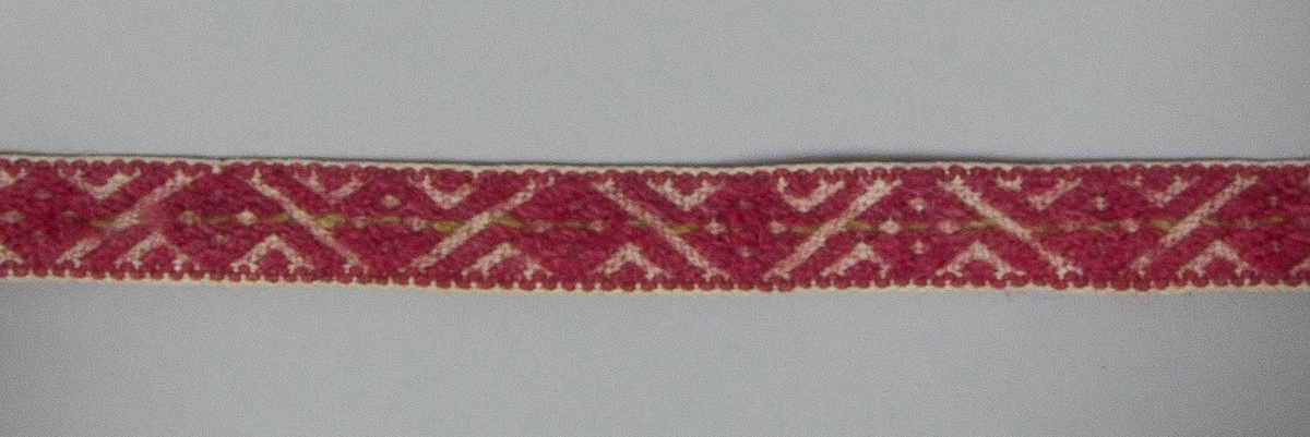 Kjolsäck till dräkt för kvinna från Mora socken, Dalarna. Modell med avskuret framstycke. Tillverkad av handvävt linnetyg, vävt i korndräll. Breda fållar i överkanterna. Handsydd förstärkning ovanför sidsömmarna. Axelband handvävt med plockat mönster av rött och lite grönt ullgarn på vit linnebotten.
