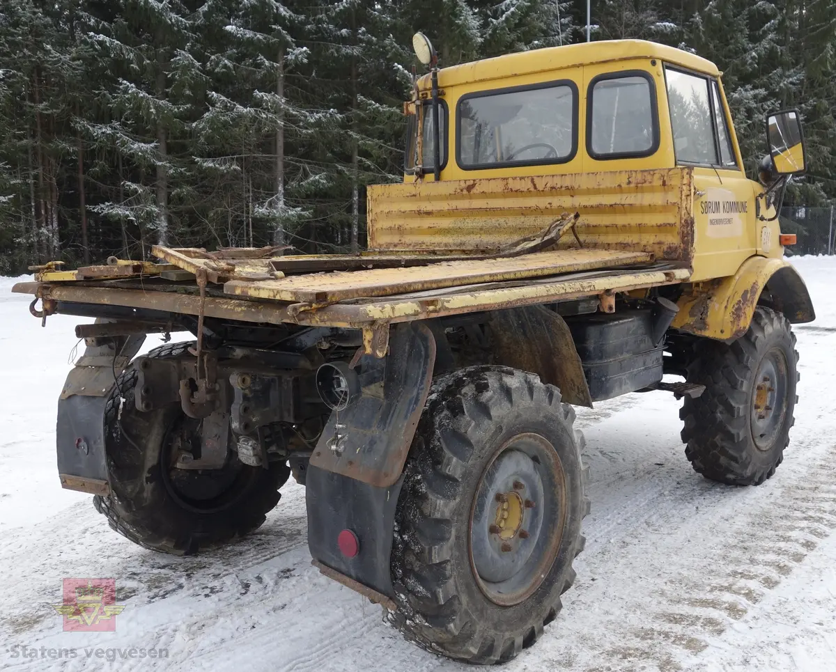 MB Unimog 406. Lastebil på 4 hjul, (to akslet), med akselavstand 240 cm. I hovedsak gul. 4-hjuls drift. Kjøretøyet har for fremdrift en 6-sylindret dieselmotor, antatt av typen M.B OM 352 X 11 fra Mercedes Daimler Benz. Motoren yter 84 Hk (61,76 KW) og har et slagvolum på 5700 kubikkcentimeter.
Schmidt standard frontmontert redskapsfeste. Antall seter er 2. Standard dekkdimensjon skal være 12,5-20 rundt om.