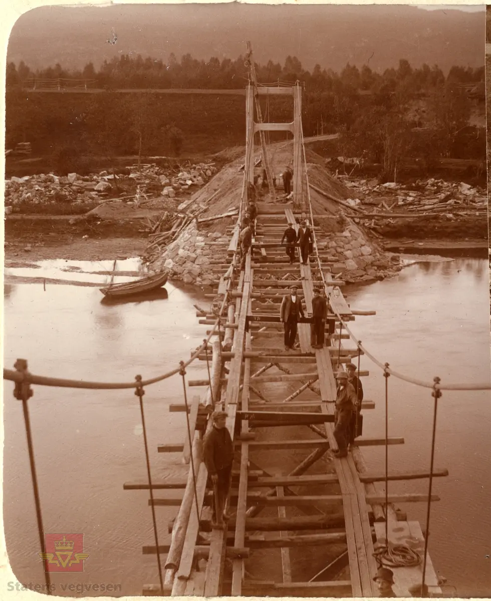 Øvre Salangen bru under bygging. Spennvidde er 54 meter. Bildet som er tatt fra ene brutårnet viser en gruppe menn i arbeid med legging av brudekke. 1913 Øvre Salangen bro stod  på brutårnet da brua var ferdig.