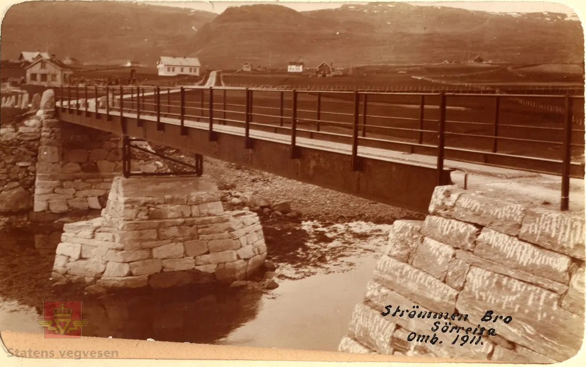 Hus og gårder i bakgrunnen. Tekst på bildet: "Strømmen Bro. Sørreisa.  Omb. 1911"
Til venstre sees gården til Daniel Solvang og Gudbrandgården, noe lengre oppe til venstre langs vegen står Straumen skole.
Til høyre er gården til Jon Bersvendsen og gården Berg, og i bakgrunnen Bollhågen.
Opplysninger fra  Guttorm Bakkehaug.