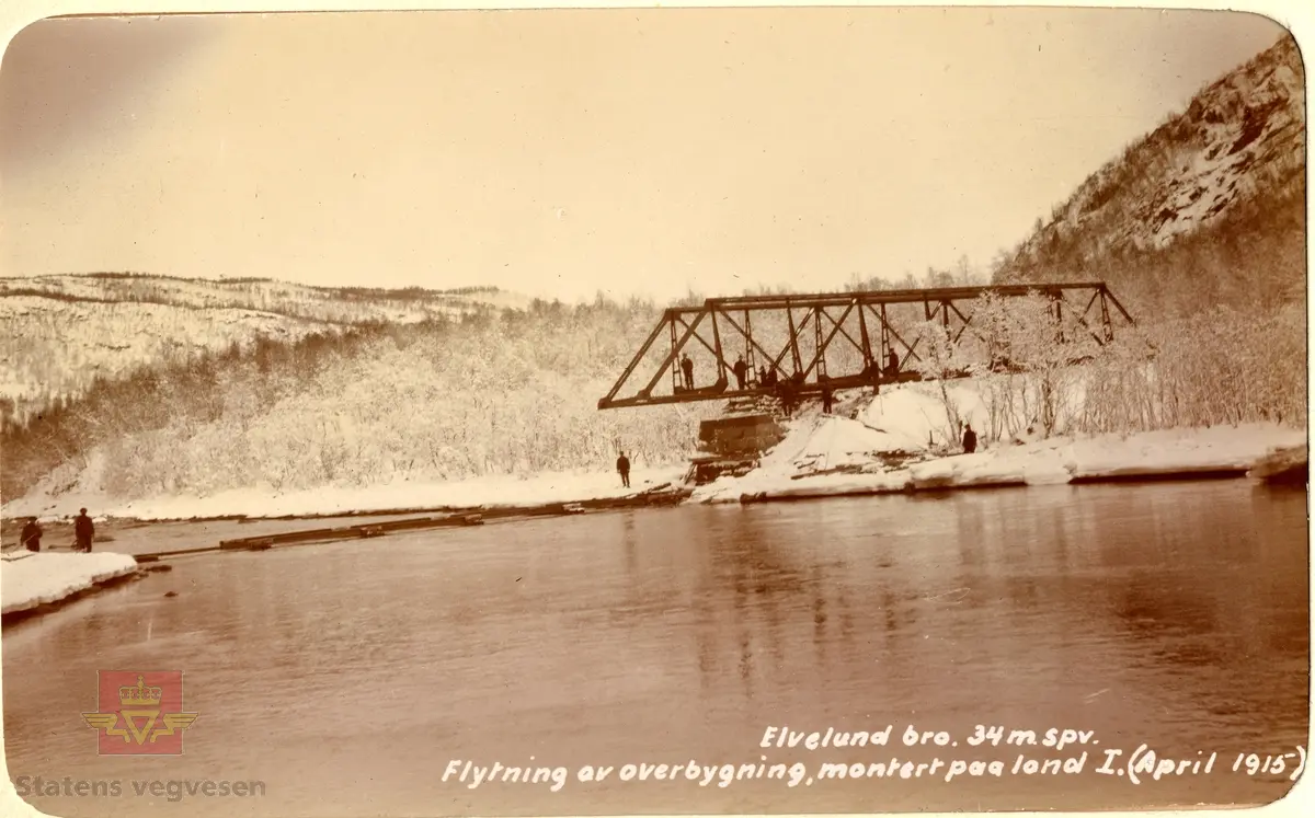 Elvelund bru i Salangen ved Laberget, Troms, under bygging.  April 1915. Stålkonstruksjonen trekkes over elva fra ene brukaret. Spennvidde er 34 meter. Tekst på bildet: "Elvelund bro. 34 m.spv. Flytning av overbygning, montert paa land I. (April 1915)"
(Opplysninger til avbildet sted fra Dag Hallgeir Tørrisen)