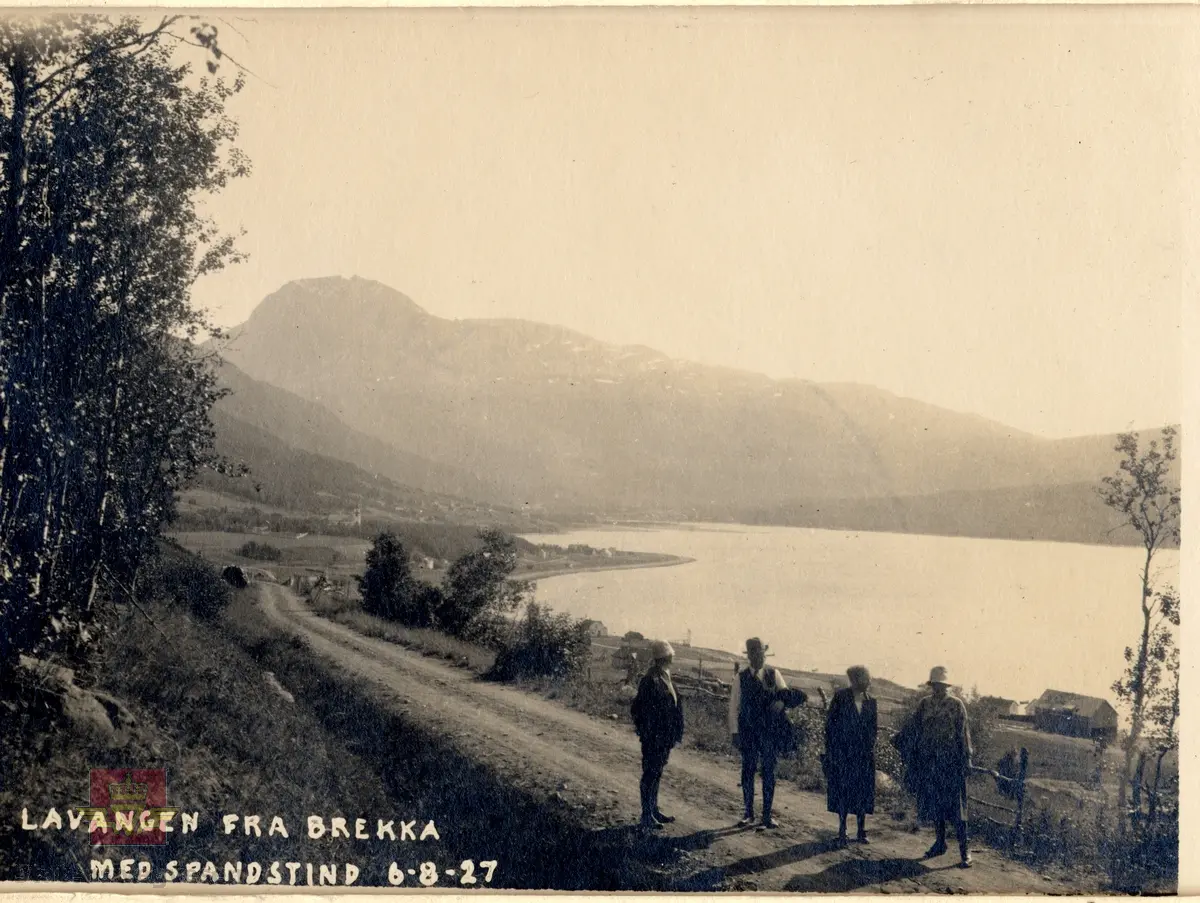 Tekst på bildet: "Lavangen fra Brekka med Spandstind 6 - 8 - 27". 
Lavangen fra Brekka med Spandstind 6. august 1927. To menn og to damer på tur langs en bygdeveg. 

10.03.2016: "Her fra Brekka ser en mot sør Spanstinden, men vannflata til høyre på bildet er fjorden i Lavangen. Odden som stikker ut i fjorden til venstre er Soløystranda." Informant til bildet er Jentoft Teigland.