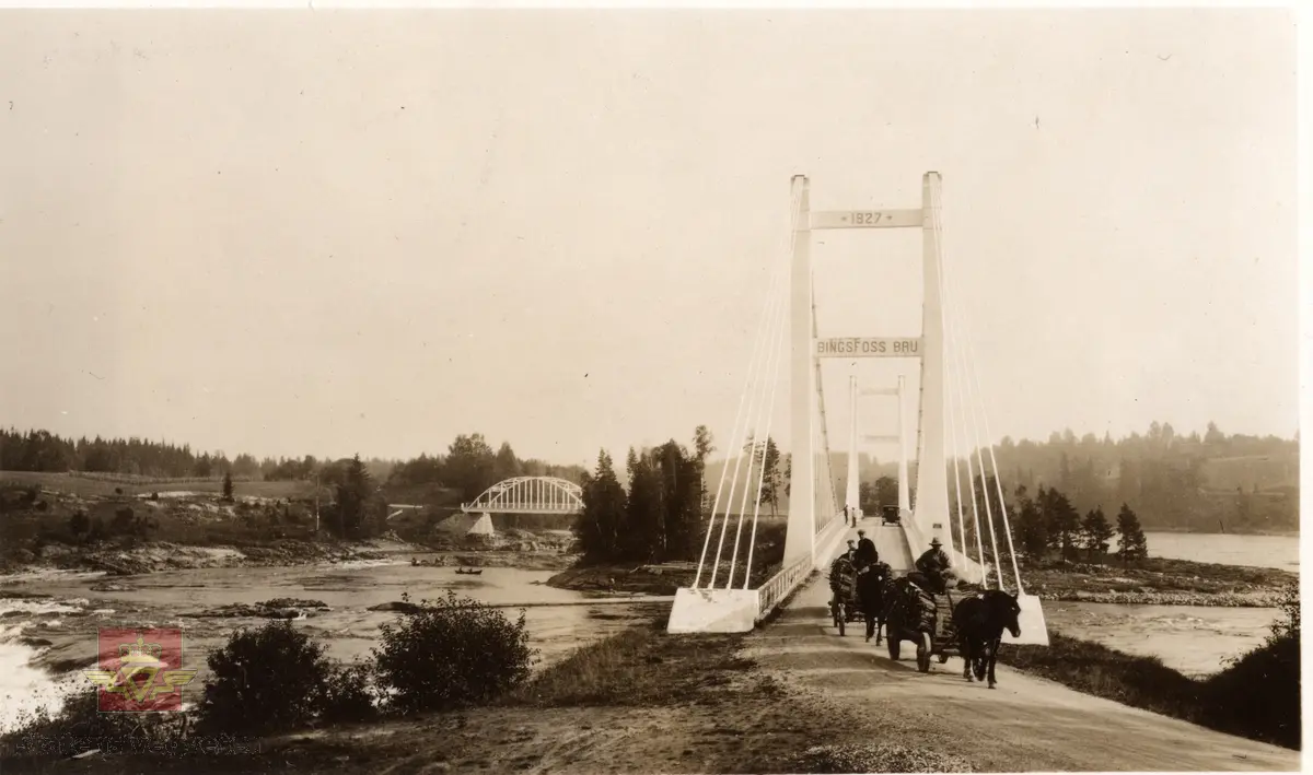 Bingsfoss bru over Glomma i Akershus.  År 1927 står skrevet på brutårnet. To lasskjørere med hest og vogn. En bil står parkert på brua. Buebrua synlig til venstre for holmen.