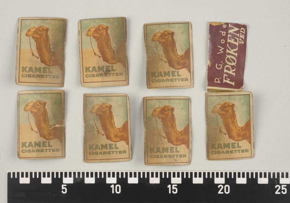 Utskåret rektangulær ramme i mørkt tre og 3 "møner". Bakplaten er i trefiber. Det er fire rom med pappkort. Kortene har påført håndskrevene tall og bokstaver som dato, måned, dag og årstall. De fleste har et bilde med en kamel på baksiden og trykt tekst. Fire av årstallkortene har påført håndskrevene navner og tall.