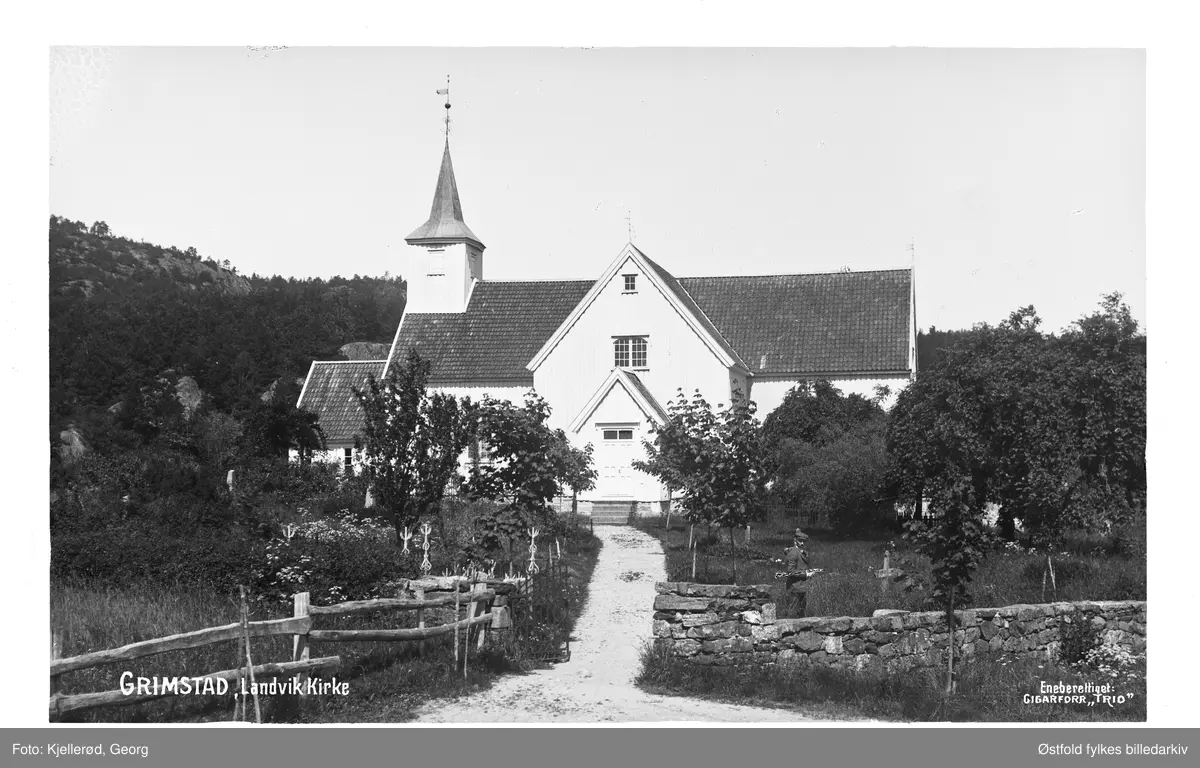 Landvik kirke, Grimstad i Aust-Agder. Mann ved kirkegårdsmuren.
Landvik kirke er en korskirke fra 1824. Byggverket er i tømmer og har 400 plasser.