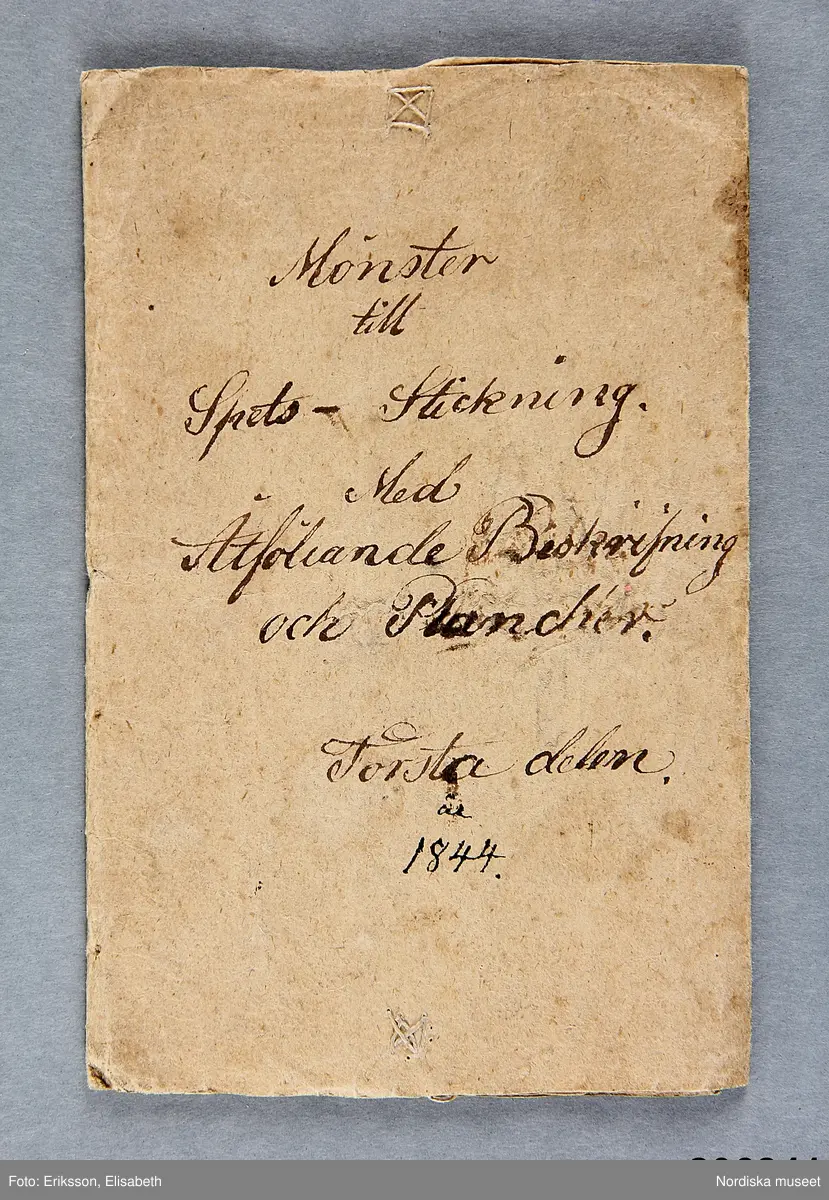 Litet hemgjort häfte med gråbrunt omslag med påskrift för hand: Mönster till Spets-Stickning med Åtföljande beskrivning och Planscher. Första delen år 1844.
 Häftet är kopierat efter ett litet tryckt häfte med titeln : Mönster till spets-stickning och hålsöm af M.C.S.......n, tryckt i Uppsala 1843. Se Nord.mus arkiv nr. 1949/15.
 /Berit Eldvik 2012-10-16