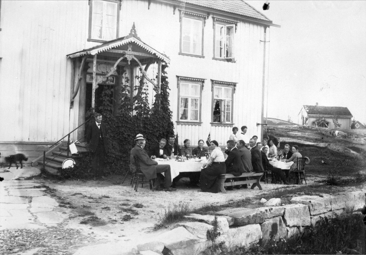 Normanfamilien samlet ved et pent dekket bord, foran et hus.