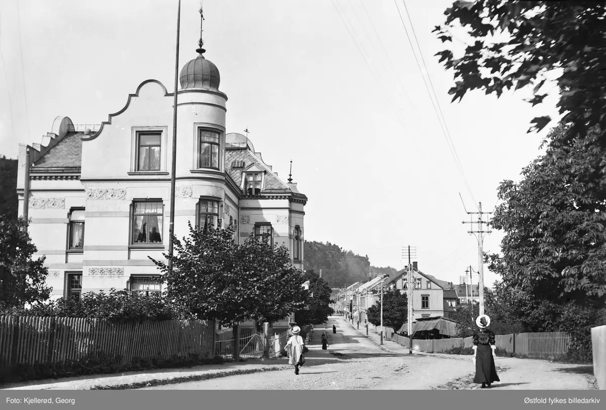 Villa og gateparti i Holmestrand. Bildet er tatt mot nord og viser Tårngården, Veien utenfor ble muligens kalt for Widemanbakken. (Langgaten). Tårngården var i privat eie til 1921 da den ble solgt til A/S Nordisk Aluminiumindustri og ble brukt til kontorer og direktørbolig. Revet.