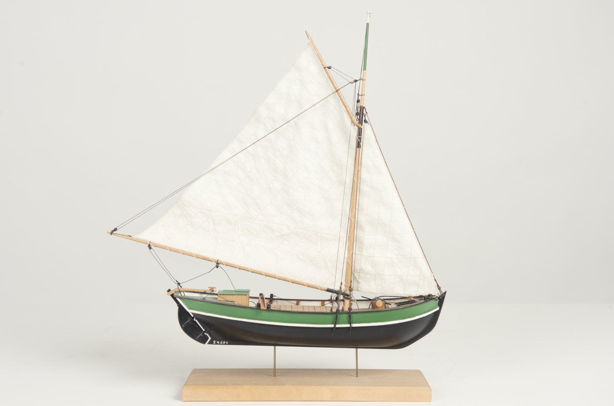 Riggad med fock och gaffelstorsegel. Svart skrov, grön bredgång. Vit kaltopp. Modellen tillverkad till utställningen "Seglande kungar, kungliga seglare", KSSS 150-årsjubileum 1980.
